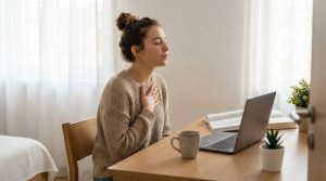 College student sitting at a desk using a breathing exercise to manage stress during a study session